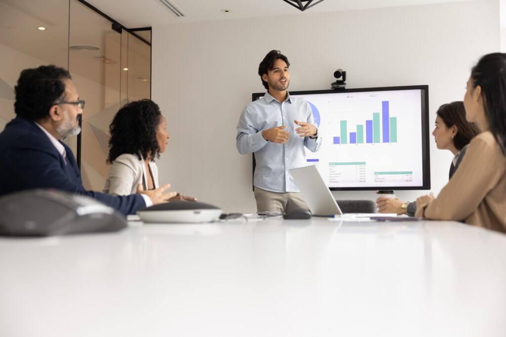 A young business professional confidently leading a team meeting, engaging colleagues in discussion.