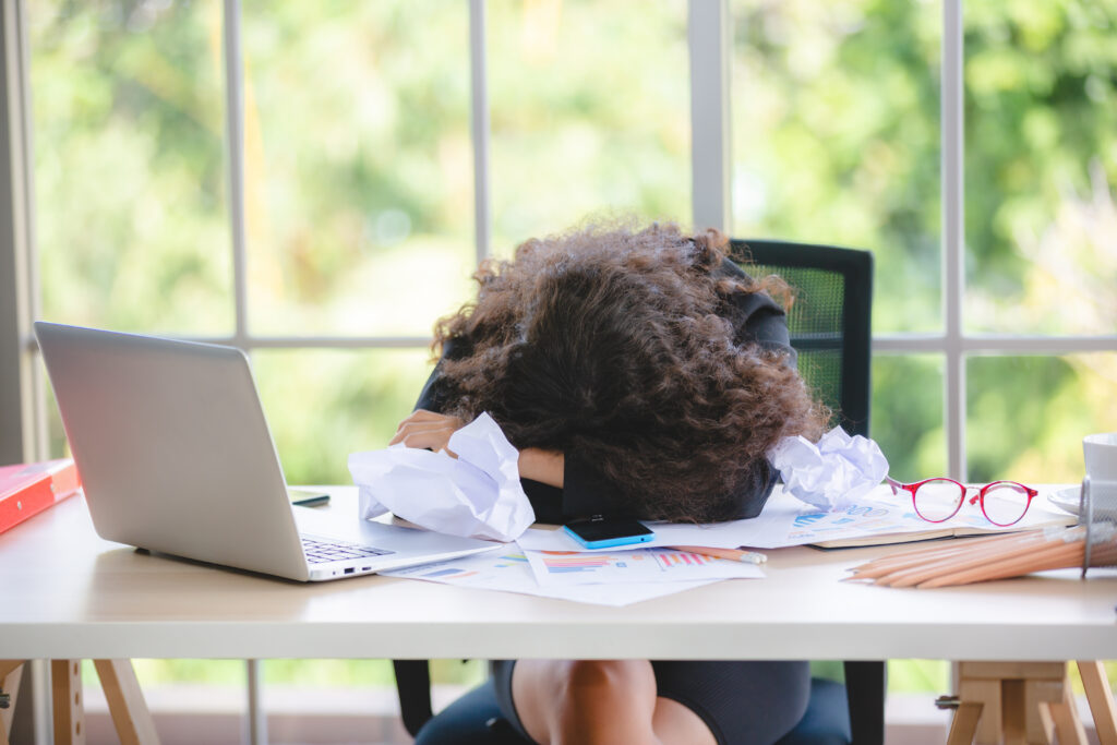 A business professional, head on desk, appearing stressed or exhausted in her office.